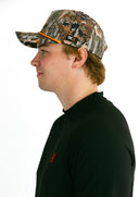 model side profile wearing camo performance hat with orange X by Nightclubssuck