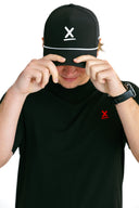 model wearing black performance hat with white X by Nightclubssuck
