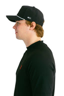 side profile of model wearing black performance hat with white X by Nightclubssuck