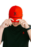 model wearing red performance hat with black X by Nightclubssuck